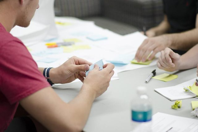 Team collaborating around a table covered in notes and devices