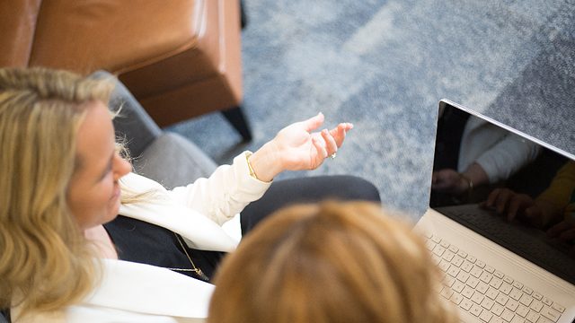 Colleague coaching another person at a laptop