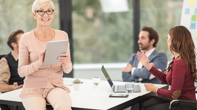 Professional presenting confidently to seated colleagues