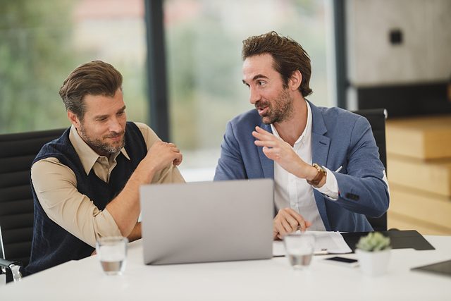 Two professionals in discussion over a laptop