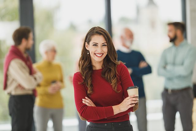 Account manager standing in an office with colleagues behind her