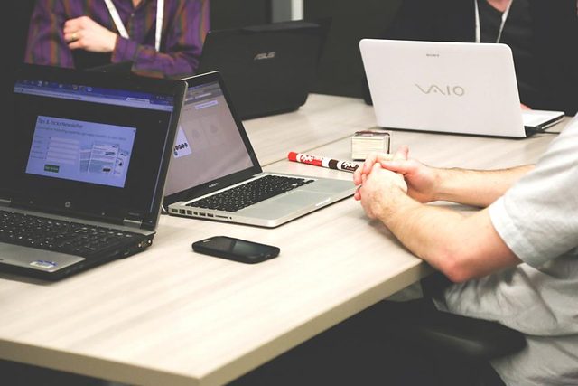 Laptops and notes spread across a desk during a planning session